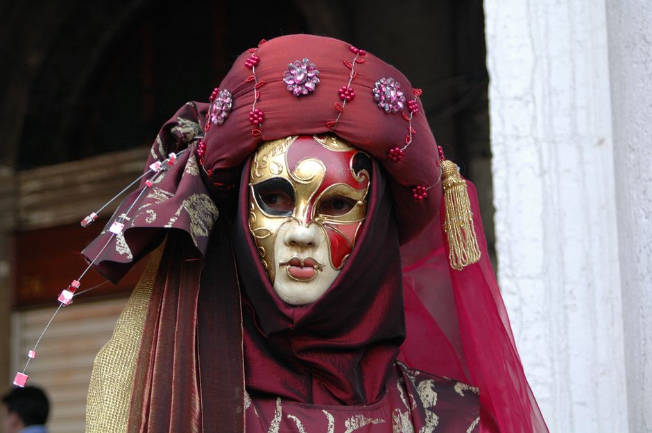 A person in an ornate Venetian mask with detailed costume, showcasing rich cultural heritage.