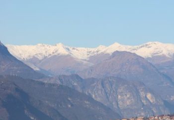 Breathtaking lake Como with snow-capped Alps in the background under clear blue skies.