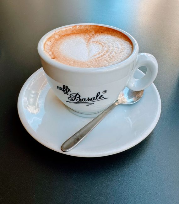 A cup of cappuccino with heart latte art served in an Italian cafe cup.