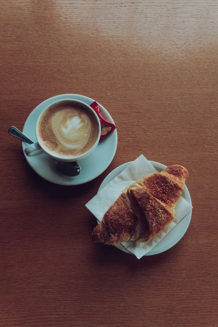 Tasty coffee and croissant on wooden table in Italian cafe, Collalbo, Italy.