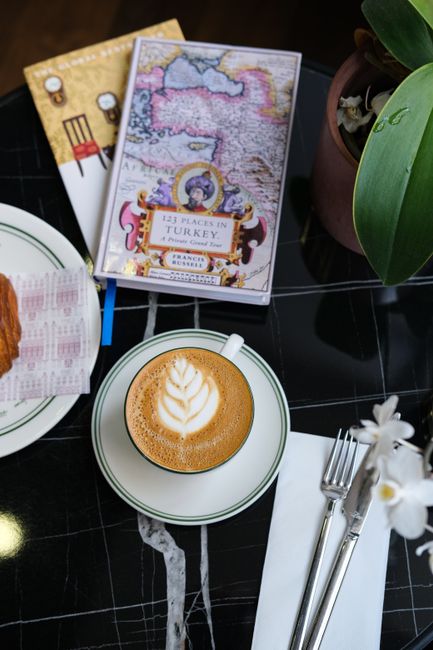 Overhead view of a cappuccino, pastry, and map of Türkiye in an Istanbul cafe setting.