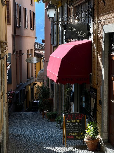 Quaint alleyway in Bellagio, Italy with a wine shop and cobbled street.