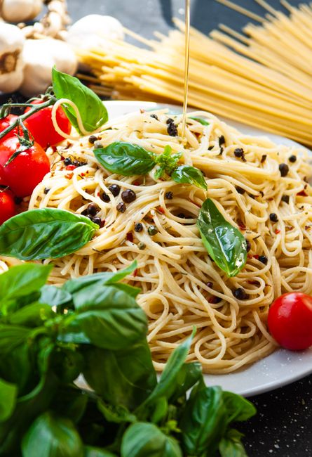 A plate of freshly made Italian spaghetti garnished with basil and cherry tomatoes.