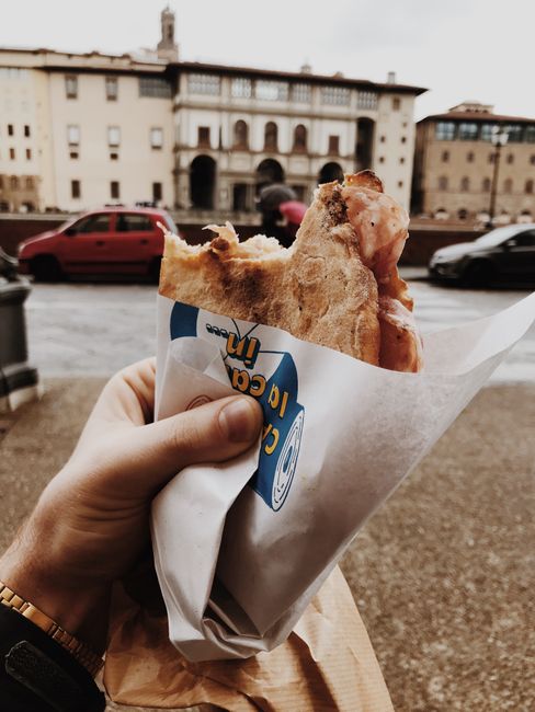 Close-up of a wrapped sandwich being enjoyed outdoors in a European urban setting.