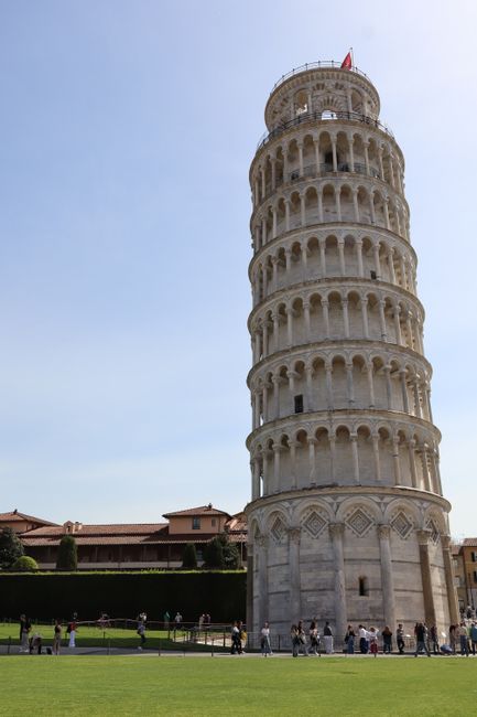 The renowned Leaning Tower of Pisa surrounded by tourists on a clear day, perfect for travel enthusiasts.