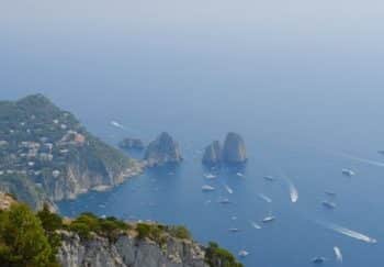 Breathtaking aerial view of Capri's cliffs and Faraglioni rocks in a tranquil summer seascape.