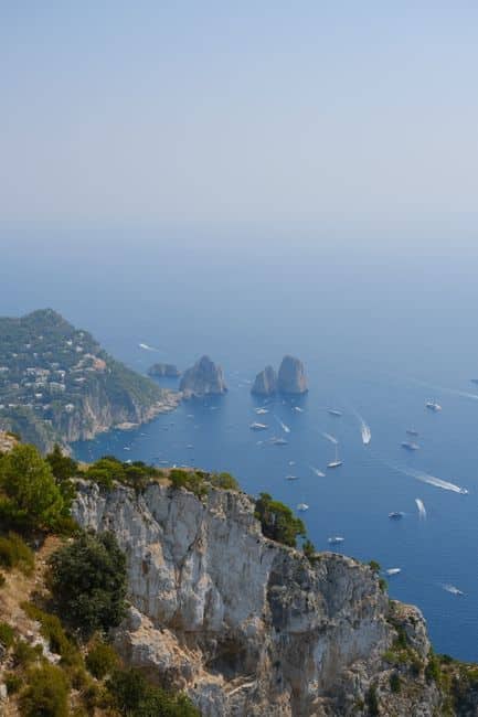 Breathtaking aerial view of Capri's cliffs and Faraglioni rocks in a tranquil summer seascape.