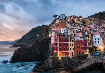 Scenic view of Riomaggiore's vibrant houses on a cliffside at sunset, Liguria, Italy.