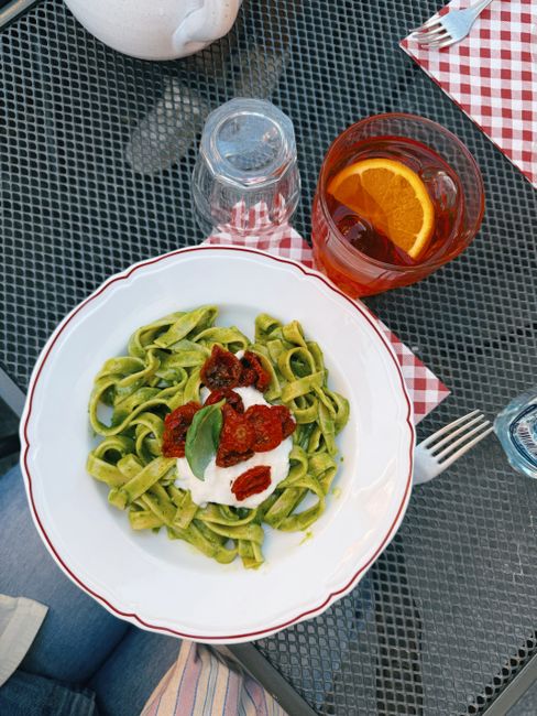 Delicious green tagliatelle with sun-dried tomatoes and creamy sauce, served outdoors in Milan, Italy.