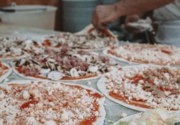 Authentic Italian pizzas being meticulously prepared in a Roman kitchen, showcasing fresh toppings.