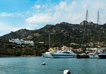 Discover the stunning marina of Porto Cervo, Sardinia with luxurious yachts against scenic hills.