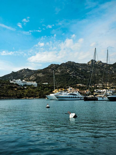 Discover the stunning marina of Porto Cervo, Sardinia with luxurious yachts against scenic hills.