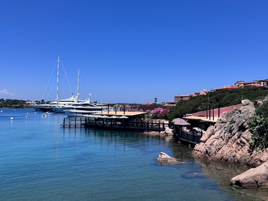 A stunning view of yachts docked along the coastline in Porto Cervo, Sardinia on a clear summer day.