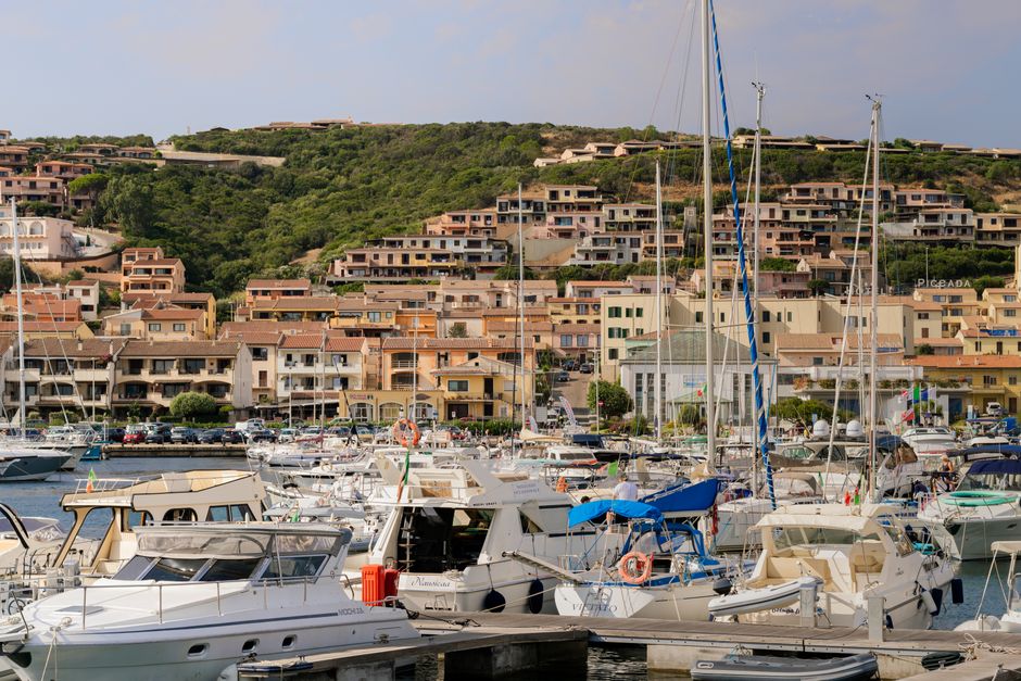 Picturesque view of Porto Cervo Marina in Sardinia with yachts and hilltop houses.