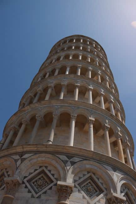 A low angle view of the iconic Leaning Tower of Pisa against a clear blue sky in Italy.