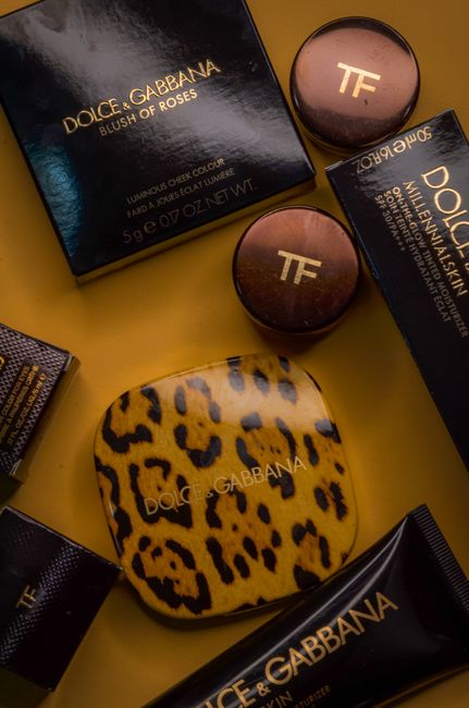 High-end makeup products arranged artfully on a bold yellow backdrop.