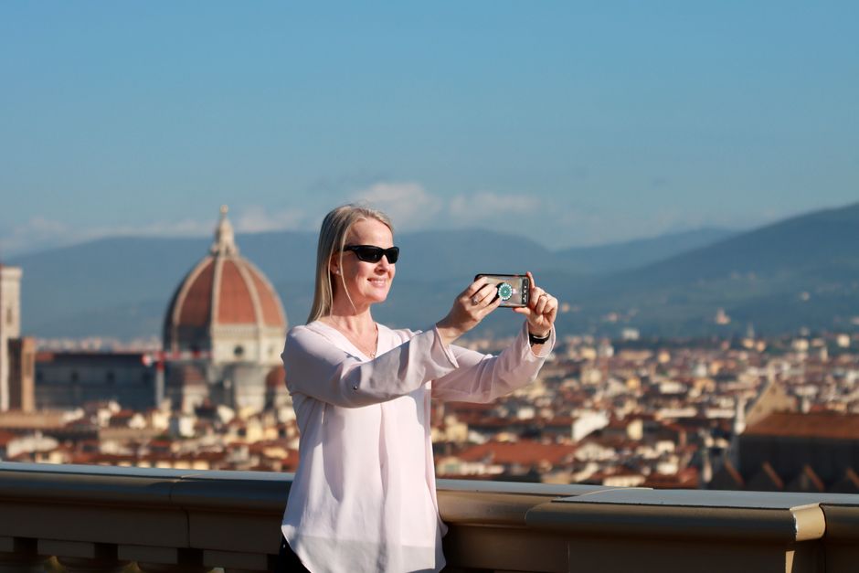 Woman in sunglasses takes selfie overlooking Florence Cathedral in sunny Florence, Italy.