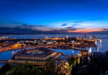 A breathtaking aerial view of Ancona port at sunset, showcasing vivid colors and industrial docks.