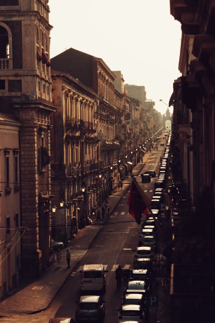 Captivating aerial view of Catania's urban street with historic architecture and traffic at sunset.