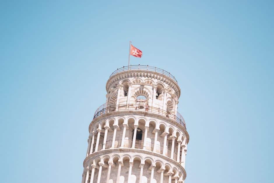 Part of the famous Leaning Tower of Pisa against a clear blue sky in Italy.