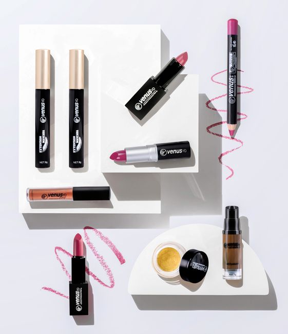 Stylish flat lay of various makeup products including lipstick, eyeliner, and mascara on a white background.