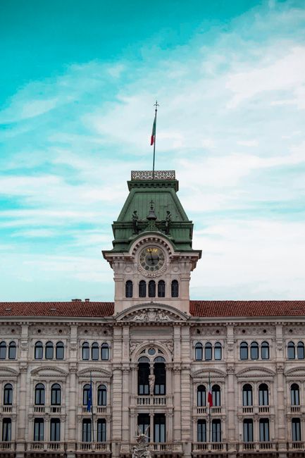 Historic Palazzo del Municipio in Trieste, Italy with a striking clock tower and Italian flag.