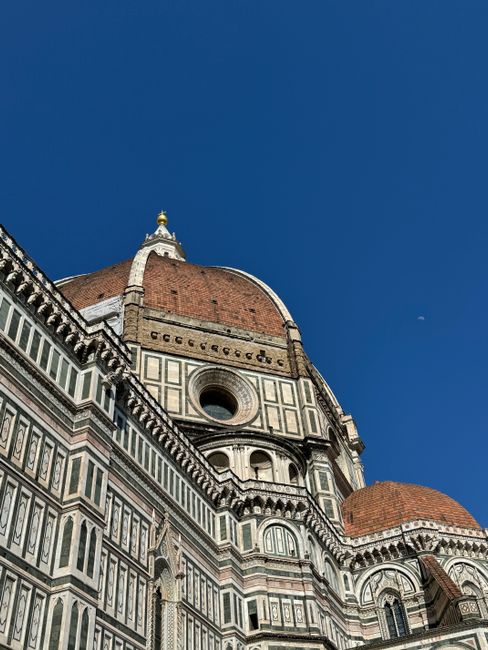 Close-up view of Florence Cathedral's iconic dome against a bright blue sky.