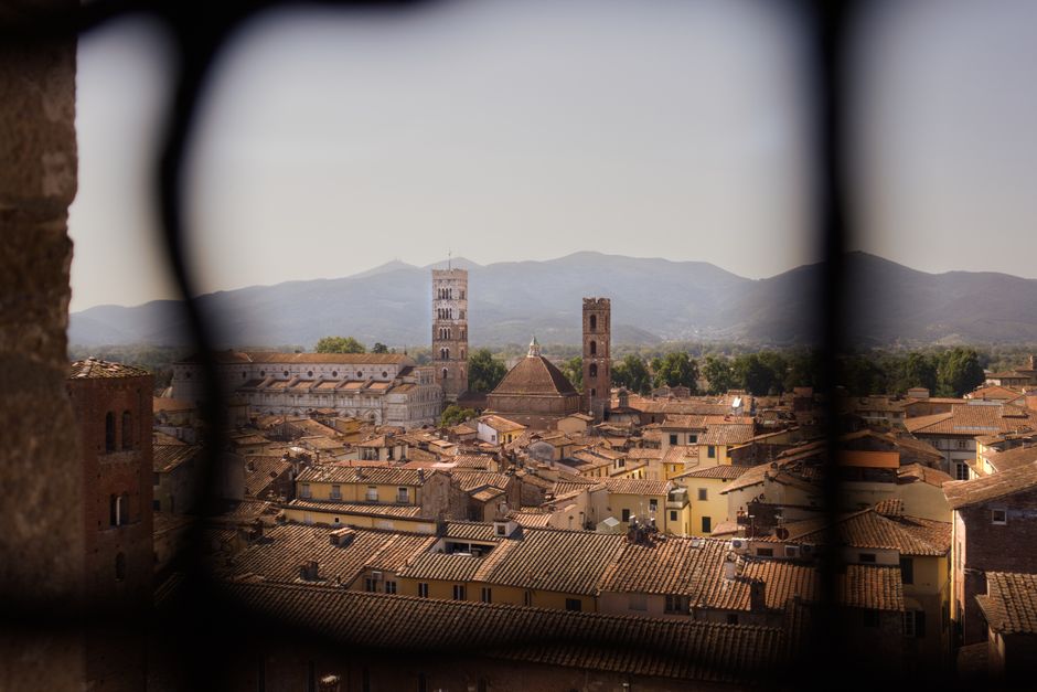 Beautiful aerial view of Lucca's medieval architecture with mountains in the background.