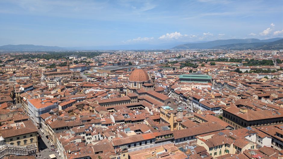 A stunning aerial view of Florence with iconic red rooftops and historic landmarks on a clear day.
