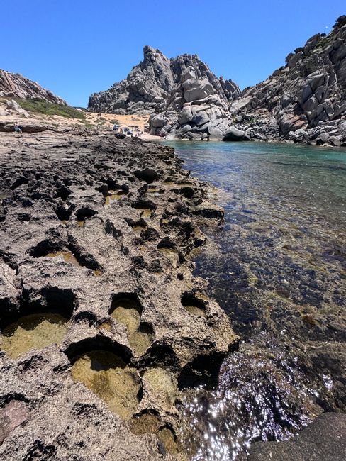 Stunning view of rocky coastline and clear waters in Sardinia, Italy, under a bright summer sky.