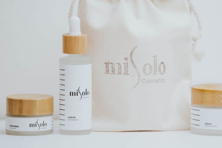 Elegant skincare products with wooden lids and a branded pouch, showcasing minimalist design.