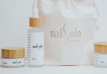 Elegant skincare products with wooden lids and a branded pouch, showcasing minimalist design.