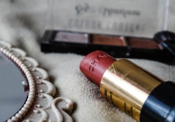 Close-up shot of a lipstick and makeup palette on a textured surface, ideal for beauty branding.