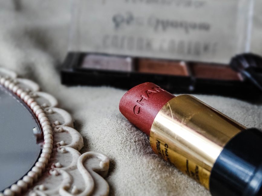 Close-up shot of a lipstick and makeup palette on a textured surface, ideal for beauty branding.