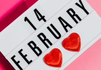 Bright Valentine's Day sign with hearts on a vibrant pink background, perfect for February 14 celebrations.