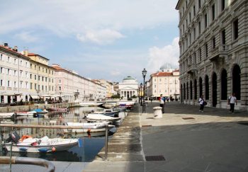 Scenic view of boats on a canal flanked by classic urban architecture and clear sky.