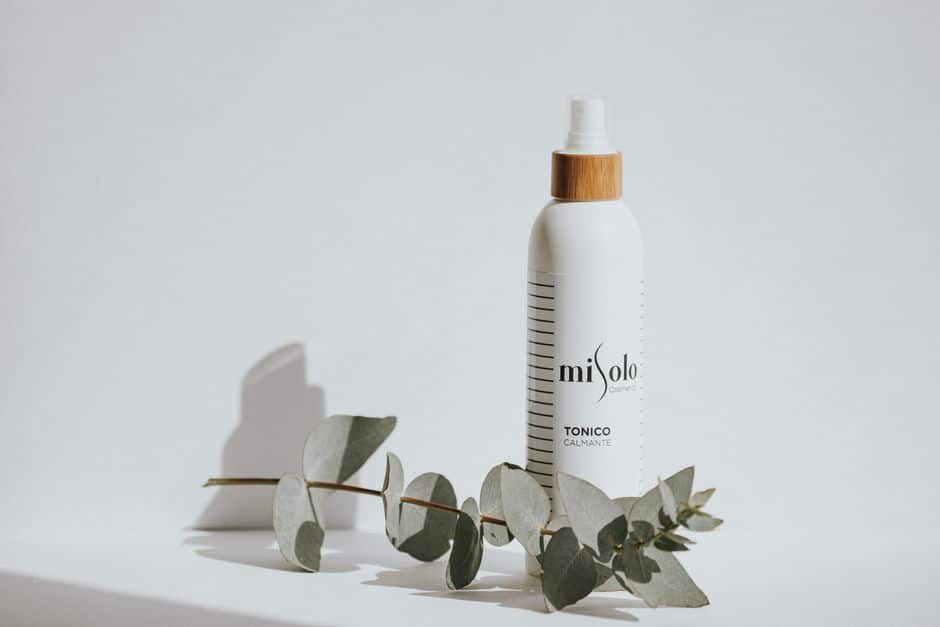 Calming toner bottle with eucalyptus leaves on a white background for skincare branding.