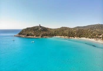 A scenic aerial view of the Porto Giunco Tower and turquoise waters in Villasimius, Sardinia, Italy.