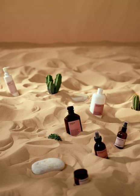 Skincare products artfully displayed on sand with a desert theme.