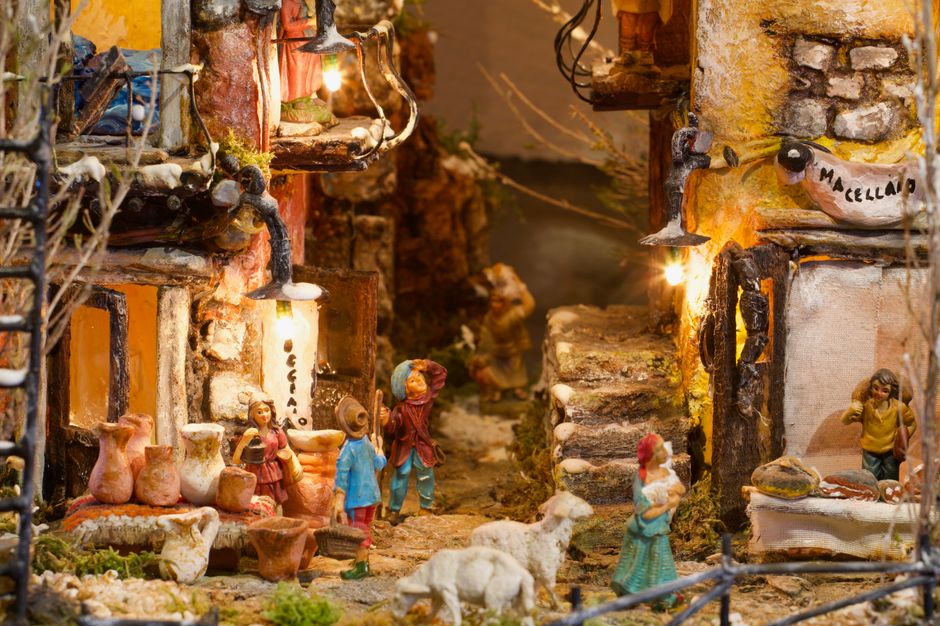 Intricate nativity scene in Toscana, Italy depicting village life with figurines and warm lighting.