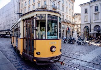 Classic yellow tram in a busy European city street showcasing architecture and urban life.