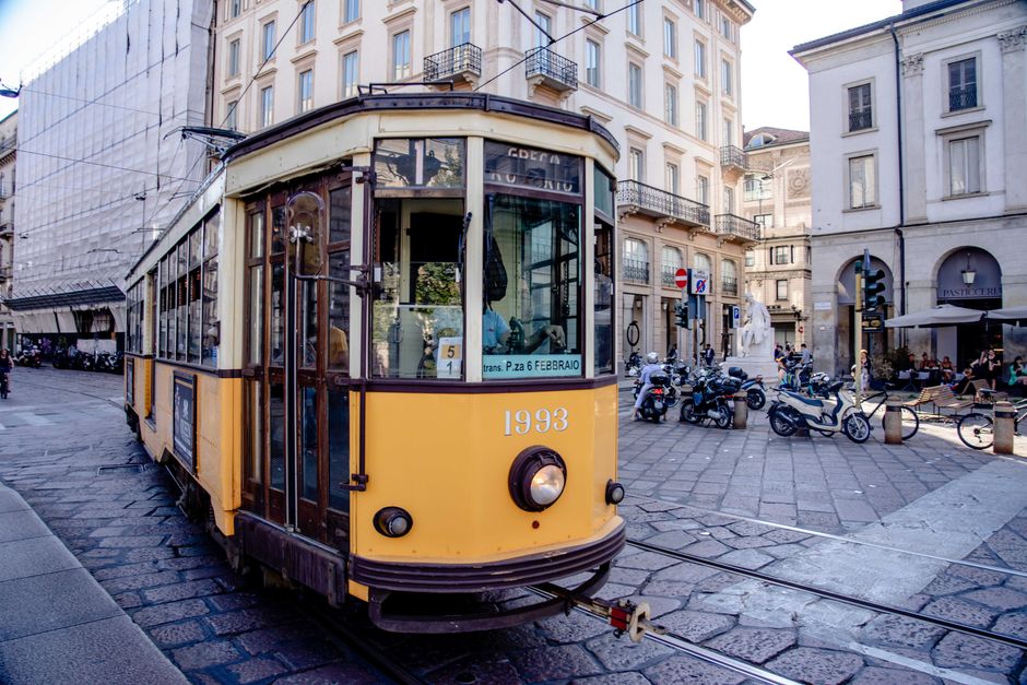 Classic yellow tram in a busy European city street showcasing architecture and urban life.