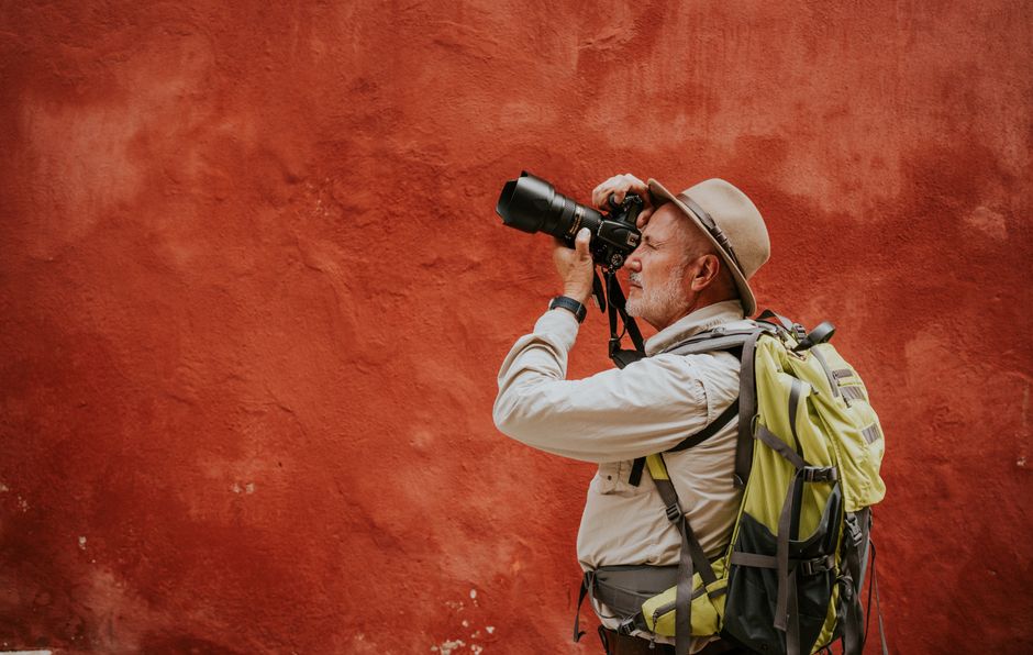 Senior man photographing in Guanajuato, Mexico with a DSLR camera and backpack.