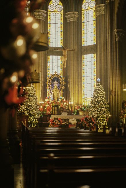A beautifully decorated church interior featuring stained glass windows and festive decorations.