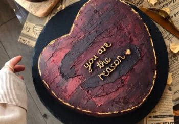A heart-shaped cake with 'you are the reason' on a tray, perfect for celebrations.