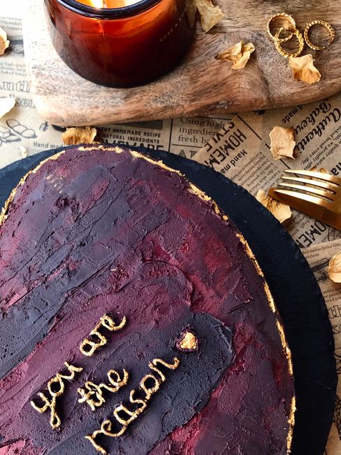 A dark red rustic cake with a heartfelt message, surrounded by cozy elements and warm tones.