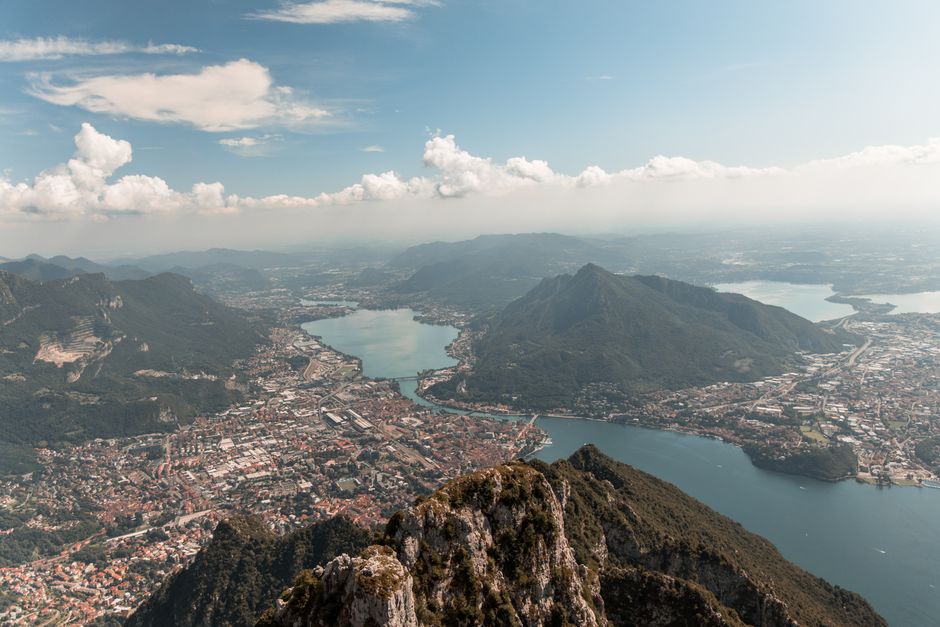 Breathtaking aerial view of Lake Como surrounded by lush mountains and picturesque towns under a clear blue sky.