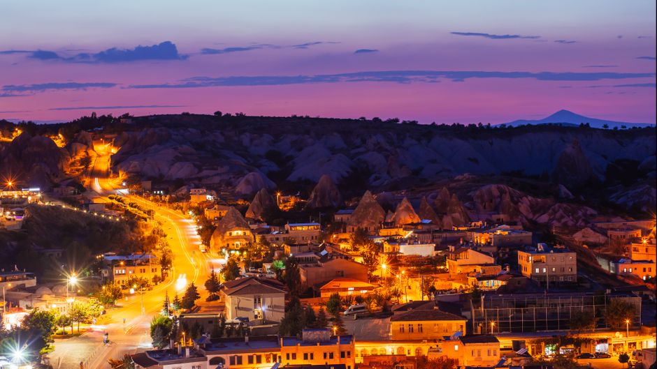 Stunning aerial view of Göreme National Park in Cappadocia, Turkey at twilight, showcasing illuminated landscapes and unique rock formations.