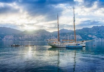 Peaceful sailboat scene on Lake Garda during sunset in Veneto, Italy.