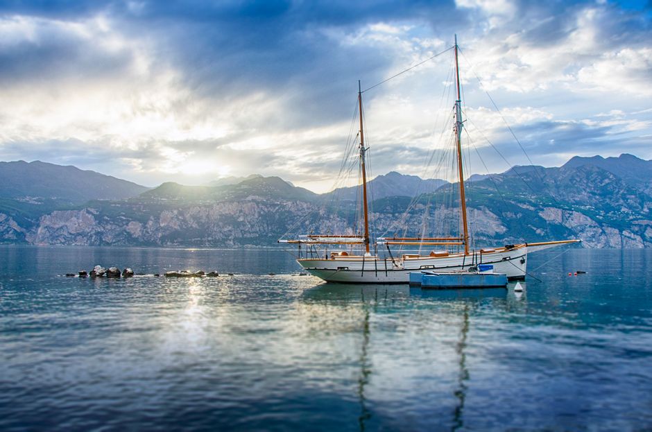 Peaceful sailboat scene on Lake Garda during sunset in Veneto, Italy.